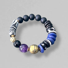 Load image into Gallery viewer, purple, black, white, and brass beaded bracelet on a gray background