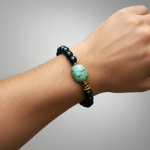 Load image into Gallery viewer, Bracelet with black and turquoise beads on a wrist against a gray background