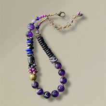 Load image into Gallery viewer, Beaded statement necklace with purple and black beads on a beige background