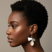 Load image into Gallery viewer, Woman wearing a shell and bone earring against a neutral background