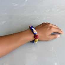 Load image into Gallery viewer, Hand wearing a colorful beaded bracelet on a light gray background