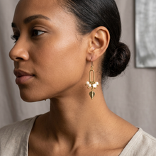 Load image into Gallery viewer, A close-up side profile of a woman wearing a delicate gold dangle earring with small white pearl-like beads and a gold teardrop charm, against a soft neutral background.