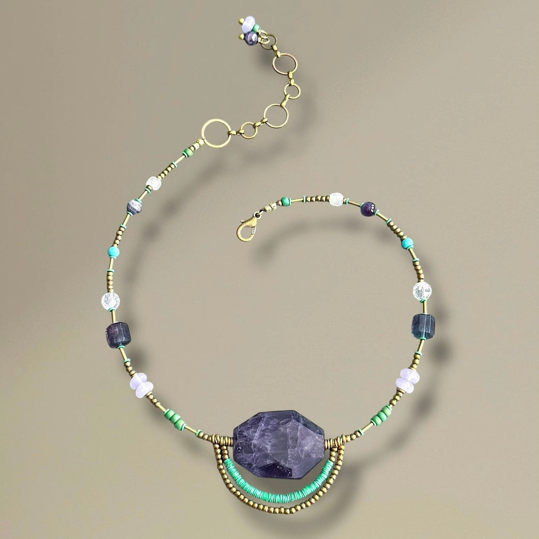 Necklace with purple stone and multicolored beads on a beige background