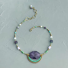 Load image into Gallery viewer, Necklace with beads and a large purple stone on a textured gray background