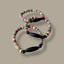Load image into Gallery viewer, Three colorful beaded bracelets with black wooden toggle clasp, arranged on a solid taupe background.