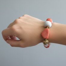 Load image into Gallery viewer, Hand wearing a pink and white beaded bracelet on a plain grey background
