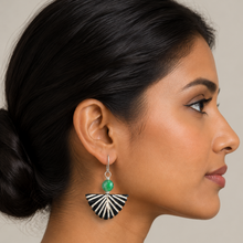 Load image into Gallery viewer, A close-up side profile of a woman wearing a dangling earring. The earring has a silver-toned hook, a round green stone, and a fan-shaped drop with black and white striped segments.