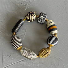 Load image into Gallery viewer, Bracelet with black, white, and gold beads on a gray background