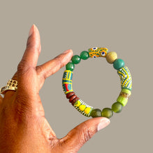 Load image into Gallery viewer, A hand holding a beaded bracelet made of green and yellow patterned beads, with a yellow snake head charm, against a solid gray background.