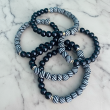 Load image into Gallery viewer, Set of black beaded bracelets with striped patterns on a marble surface
