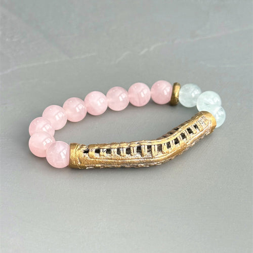 Bracelet with rose quartz and aquamarine beads with a brass accent on a gray background.