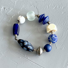 Load image into Gallery viewer, Beaded bracelet with blue, white, and patterned beads on a textured gray background
