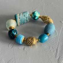Load image into Gallery viewer, Bracelet with blue and gold beads on a textured gray surface