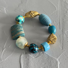 Load image into Gallery viewer, Bracelet with blue and gold beads on a textured gray surface