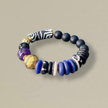 Load image into Gallery viewer, purple, black, white, and brass beaded bracelet on a gray background