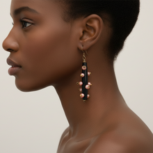 Load image into Gallery viewer, Side profile of a Black woman wearing black and pink pearl drop earrings s against a neutral background
