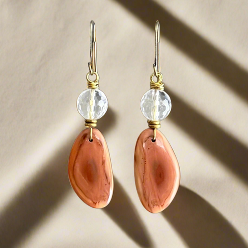 Pair of earrings with peach-colored Imperial Jasper and quartz stones on a beige background