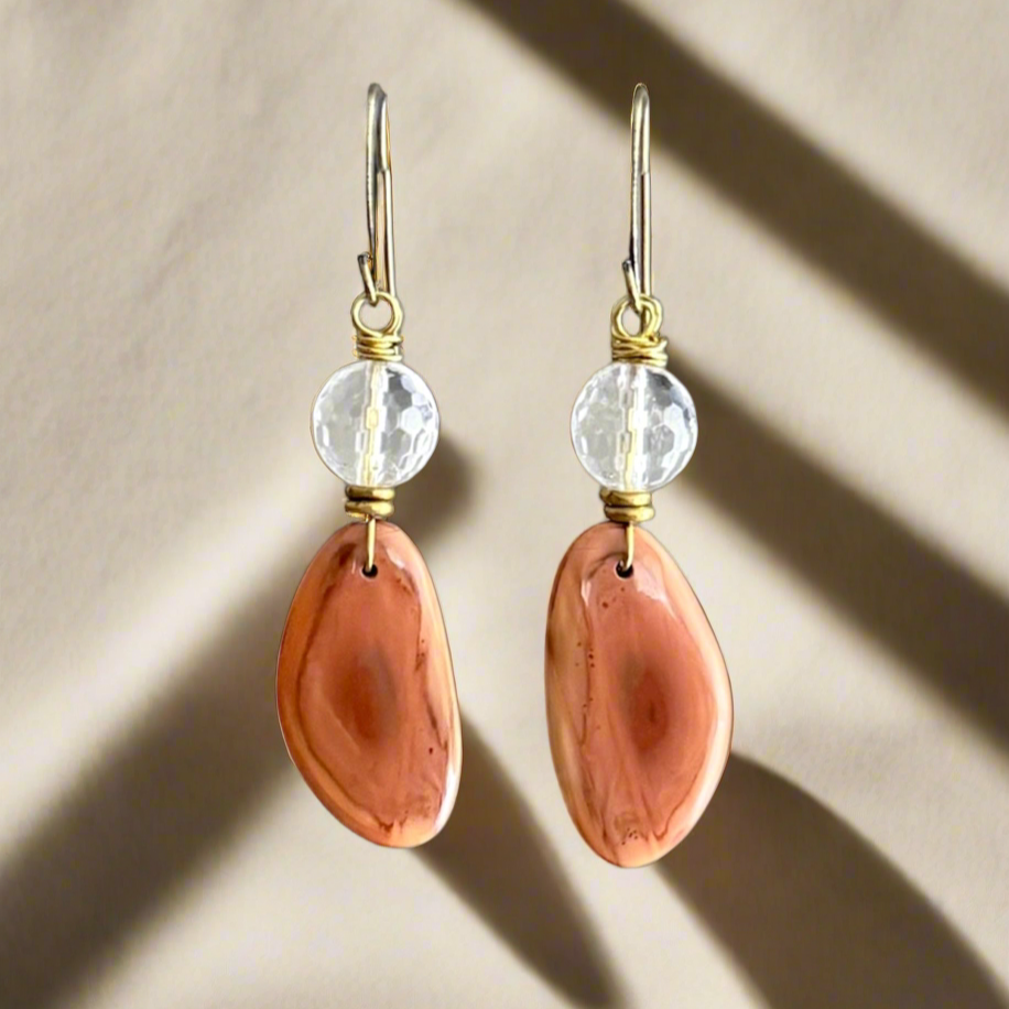Pair of earrings with peach-colored Imperial Jasper and quartz stones on a beige background