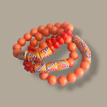 Load image into Gallery viewer, Three beaded stretch bracelets in orange, red, and yellow with geometric patterns, arranged on a solid taupe background.
