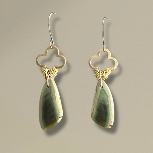 Pair of green and cream earrings on a beige background