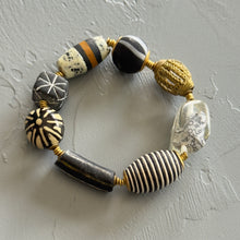 Load image into Gallery viewer, Beaded bracelet with black, white, and gold beads on a gray surface