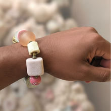 Load image into Gallery viewer, Hand wearing a bracelet with pink and white beads against a blurred background