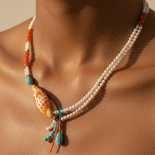 Load image into Gallery viewer, A double-strand pearl necklace with a large orange and white spotted shell pendant, turquoise beads, and small coral-colored beads, shown worn on a model's neck.