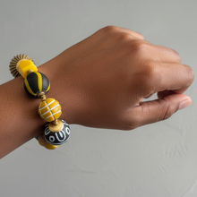 Load image into Gallery viewer, Hand wearing a colorful beaded bracelet on a neutral background