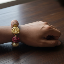 Load image into Gallery viewer, Hand wearing a bracelet with gold and red beads on a wooden surface