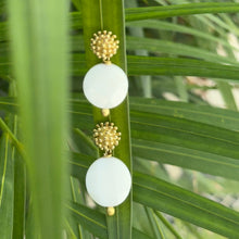 Load image into Gallery viewer, Earrings with white spherical beads and gold accents on a green leaf background