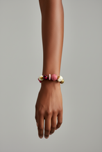 Load image into Gallery viewer, Hand wearing a colorful bracelet on a plain background