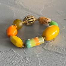 Load image into Gallery viewer, Colorful beaded bracelet with gold accents on a textured gray surface