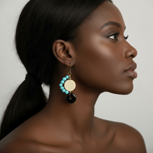 Load image into Gallery viewer, Woman wearing a pair of earrings with turquoise and black stones on a neutral background