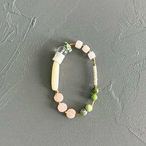 Beaded bracelet with pink, green, and white beads on a gray background