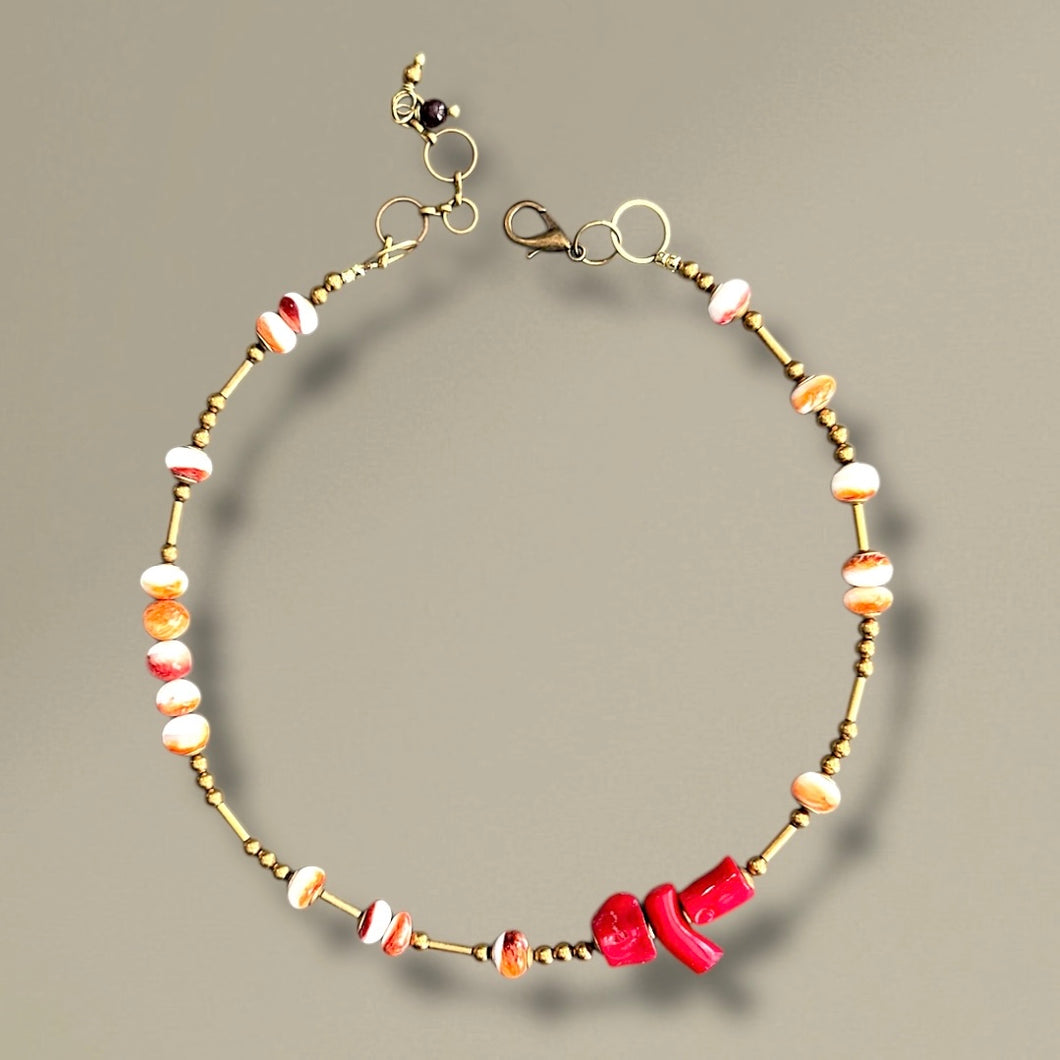 Beaded necklace with brass accents and colorful beads on a beige background