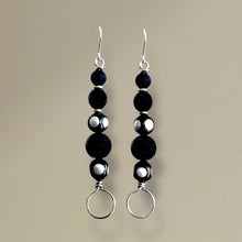 Load image into Gallery viewer, Black beaded earrings with silver loops on a beige background