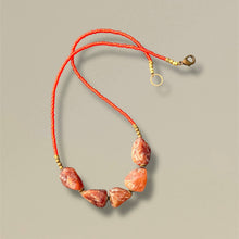Load image into Gallery viewer, Necklace with orange beads and gold accents on a beige background