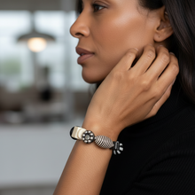 Load image into Gallery viewer, Woman wearing a silver bracelet with a blurred indoor background