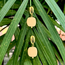 Load image into Gallery viewer, Gold earrings with wooden beads on a green leaf background