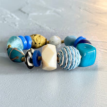 Load image into Gallery viewer, Beaded bracelet with blue, white, and gold beads on a textured surface
