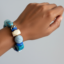 Load image into Gallery viewer, Hand wearing a colorful beaded bracelet on a gray background