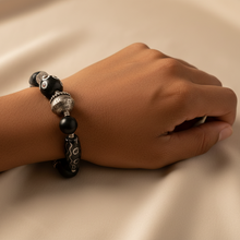 Load image into Gallery viewer, Hand wearing a black beaded bracelet on a beige background