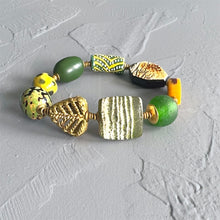 Load image into Gallery viewer, Bracelet with green, gold, and yellow beads on a textured gray background
