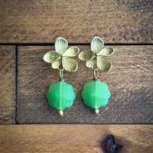 Load image into Gallery viewer, Gold flower-shaped earrings with green beads on a wooden surface