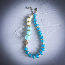 Load image into Gallery viewer, Necklace with blue and white beads on a textured gray surface