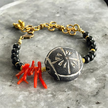 Load image into Gallery viewer, Bracelet with black beads, gold accents, and a red coral piece on a gray surface