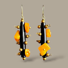 Load image into Gallery viewer, Pair of earrings with amber and black beads on a gray background