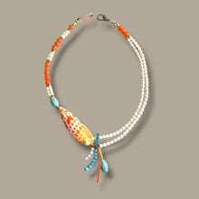 Load image into Gallery viewer, A bohemian-style double-strand necklace featuring white freshwater pearls, orange beads, turquoise beads, and a large orange-and-white patterned seashell centerpiece, displayed on a solid taupe background.