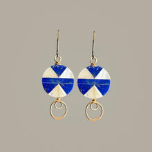 Load image into Gallery viewer, A pair of dangle earrings with circular blue and white geometric charms and gold-tone wire loops, shown against a solid taupe background.