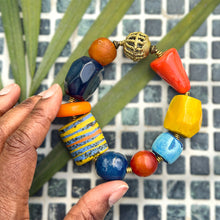 Load image into Gallery viewer, Colorful beaded bracelet held by a hand against a tiled wall background